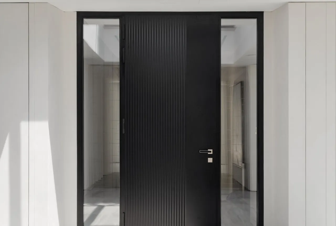 Vue intérieure d'une porte aluminium rainurée noir mat avec tierces vitrées toute hauteur