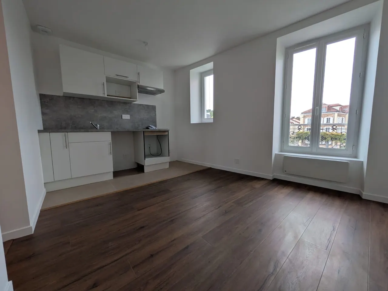 Séjour rénové avec coin cuisine, parquet foncé et deux fenêtres, à Meudon