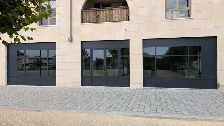 Trois vitrines de commerce en aluminium anthracite sur façade en pierre, posées par JLS Bâtiment